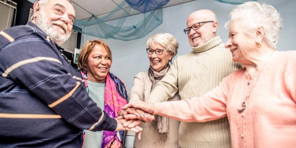 Group of elderly friends holding hands in unity.