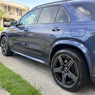 Sleek black luxury SUV parked on a driveway near grass.