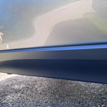 Close-up of a car door with a scratch on the lower side panel.