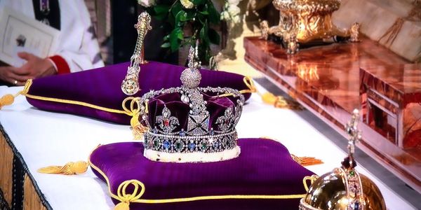 Royal crown and ceremonial items on purple velvet cushions.