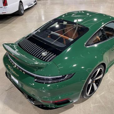 Green Porsche 911 Carrera parked indoors with sleek design.