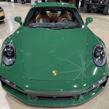 Front view of a sleek green Porsche sports car inside a showroom.