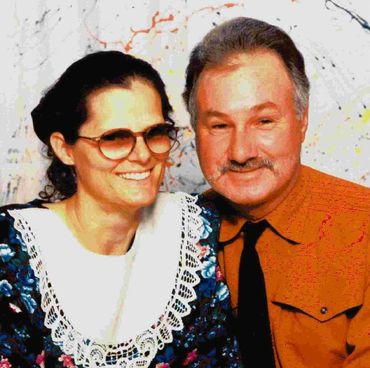 Smiling couple posing together in vintage attire.