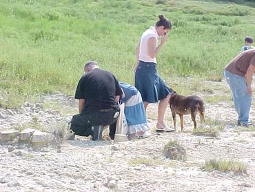 People exploring a rocky area with a dog nearby.