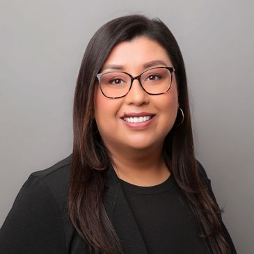 Professional woman with glasses and a black blazer smiling.