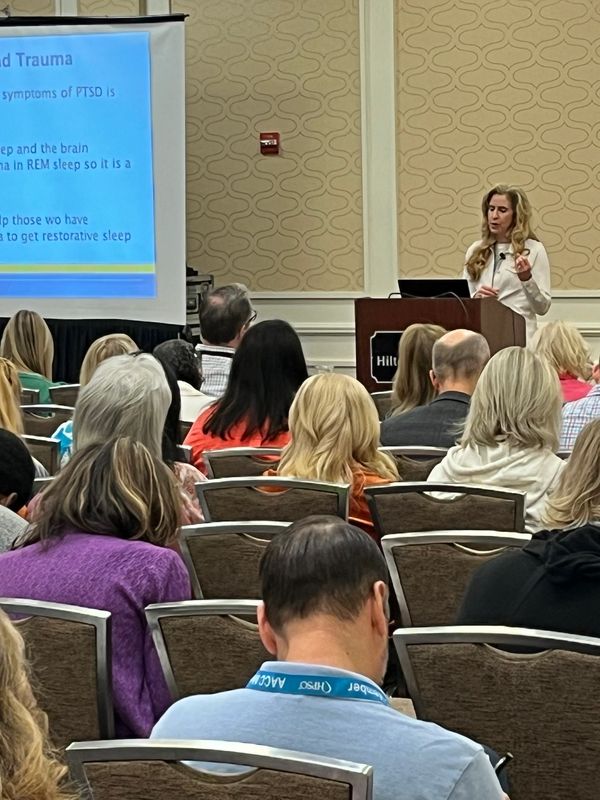 A woman is giving a presentation to an audience in a conference room.