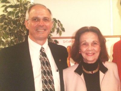 Two elderly people smiling for a photo indoors.