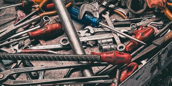 A cluttered toolbox filled with various hand tools including screwdrivers and wrenches.