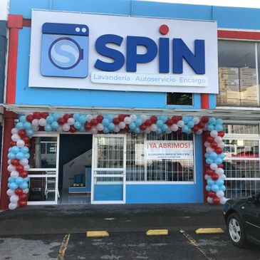 Laundry service storefront decorated with balloons and a grand opening sign.