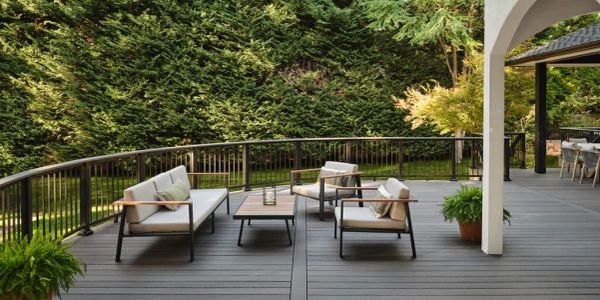 Modern outdoor patio with cushioned seating and lush greenery.