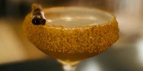 Gingerbread Dame cocktail coupe glass on bar top diffused lights in background 