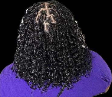 Back view of a person with curly hair and intricate braids.