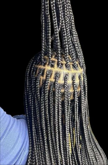 Intricate black box braids with detailed scalp parting on a person wearing a blue sleeve.