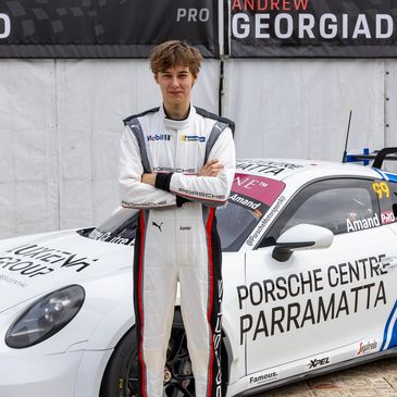 Young race car driver posing by his Porsche race car.