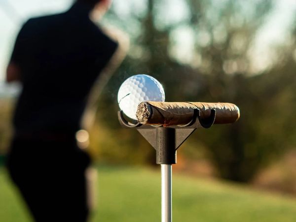 A cigar and golf club on a golf stand at a gold field