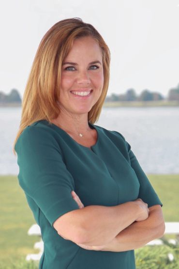 Smiling woman with arms crossed near water.