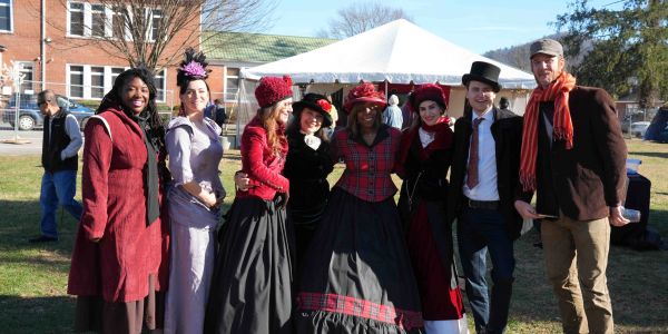 Group of people in vintage clothing posing outdoors.
