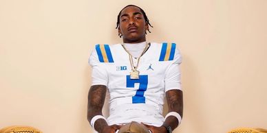 Football player in white UCLA jersey number 7.