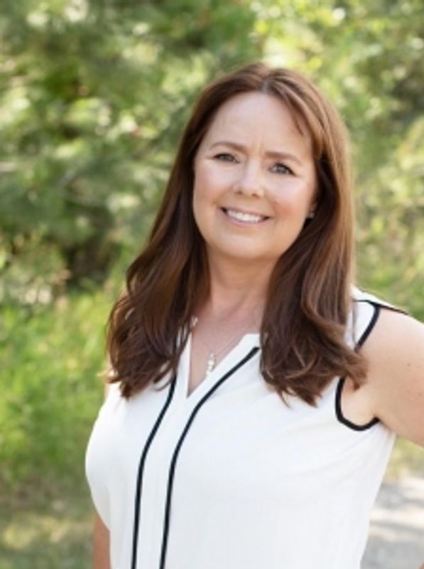 Smiling woman outdoors in a white top.