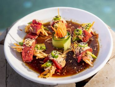 Artistic sushi rolls with fresh vegetables and sesame seeds on a white plate.