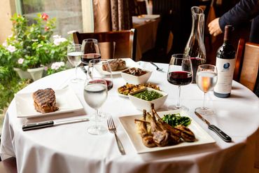 Tender roast with salad sides wine on a wooden dining table

