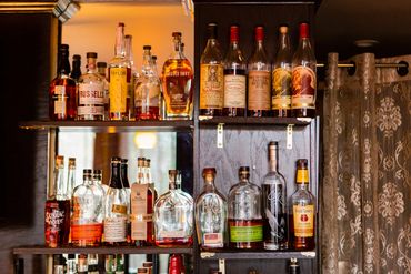 Well-stocked bar shelves with various bourbon and rye whiskey bottles