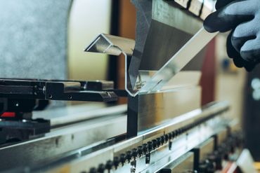 Close-up of a metal sheet being bent by a press brake machine.