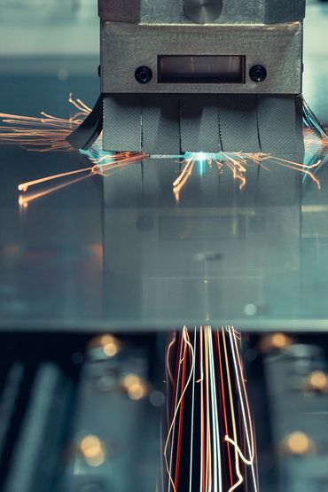 Close-up of a machine cutting metal with sparks flying.
