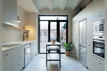 Modern kitchen with minimalist design and large glass doors opening to an outdoor area.