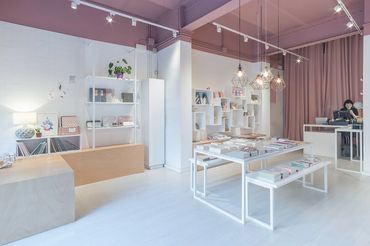 Modern stationery store with white shelves, tables, and soft lighting.