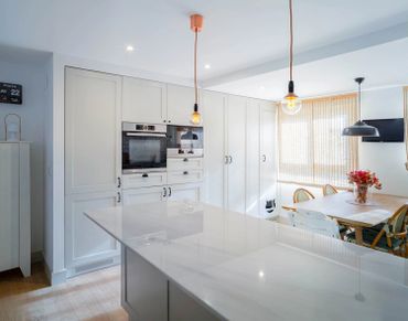 Bright modern kitchen with white cabinets and a wooden dining table.