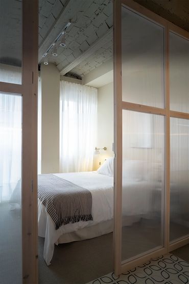 Cozy bedroom with white bedding and translucent sliding doors.