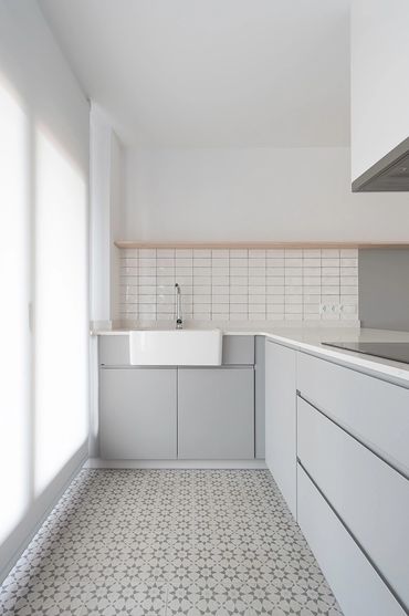 Bright minimalist kitchen with grey cabinets and patterned tile floor.