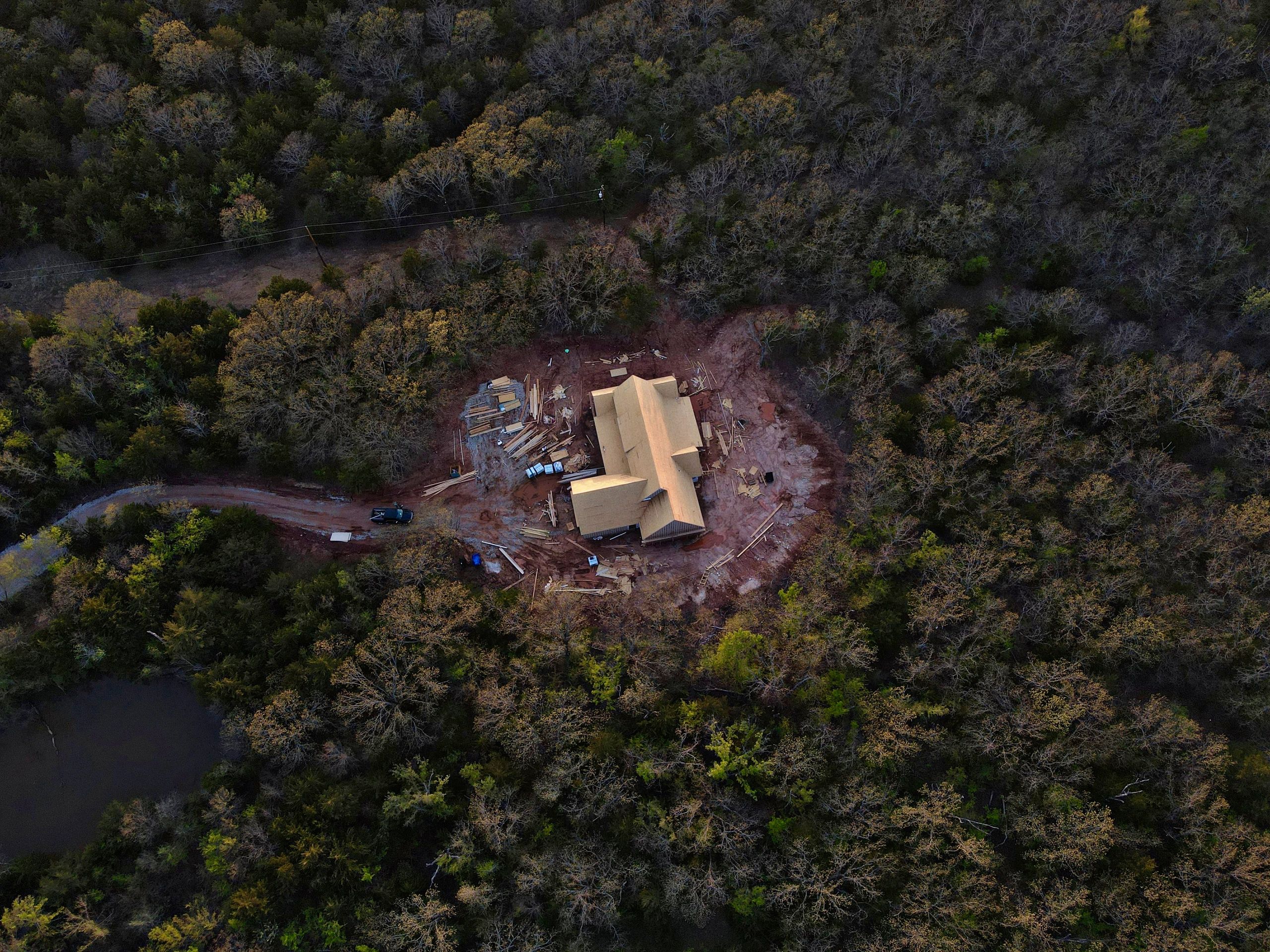 Aerial view of a house under construction surrounded by dense forest.