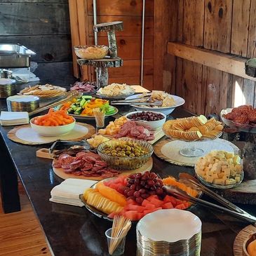 A rustic buffet table with assorted fruits, cheeses, crackers, and dips.
