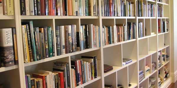 Wall-length custom bookshelf filled with books, built-in joinery, and decorative cornice detailing.