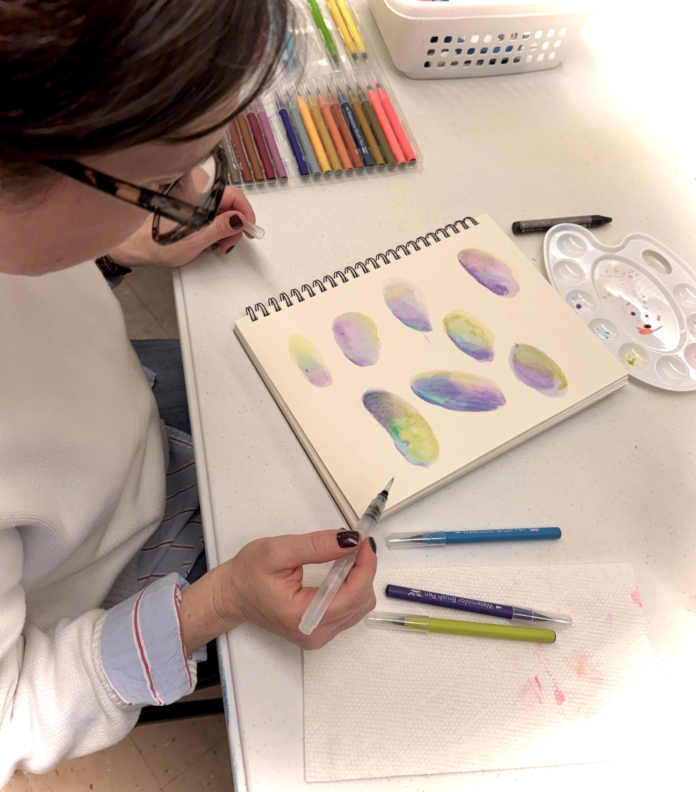 Person creating watercolor leaf paintings with brush pens.
