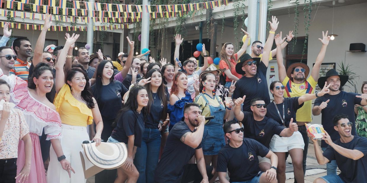 A lively group of people celebrating together with raised hands and smiles.
