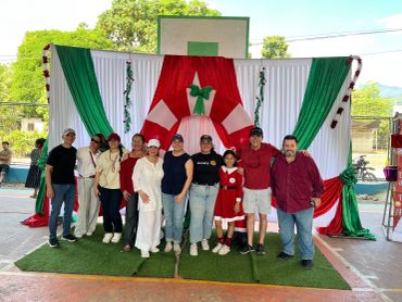 Grupo de personas en celebración navideña con decoración verde, blanca y roja.