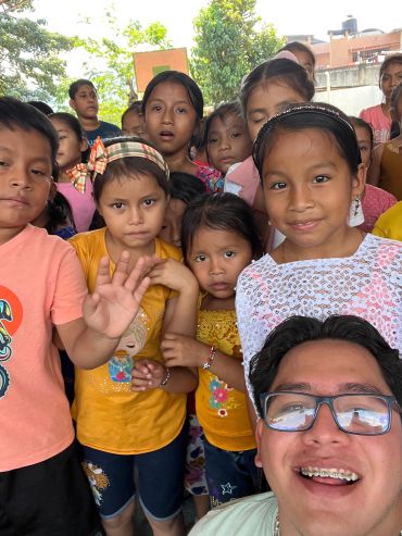 Grupo de niños y un joven sonriendo en una foto.