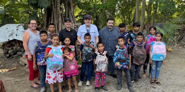 Niños con mochilas y adultos en un entorno natural.