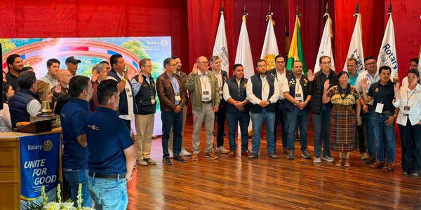 Reunión formal de grupo frente a banderas.