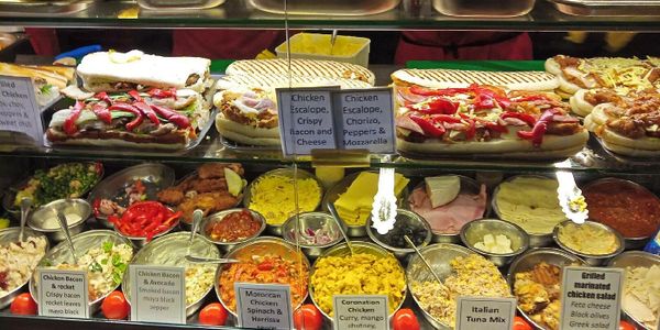 A deli display with various sandwiches, salads, and toppings.