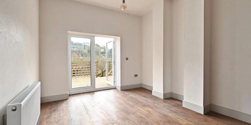 Empty room with wooden floor and glass door leading outside.