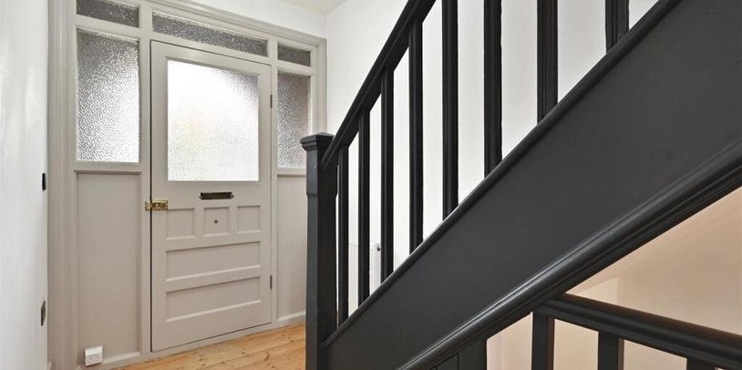 Entryway with frosted glass door and black staircase railing.
