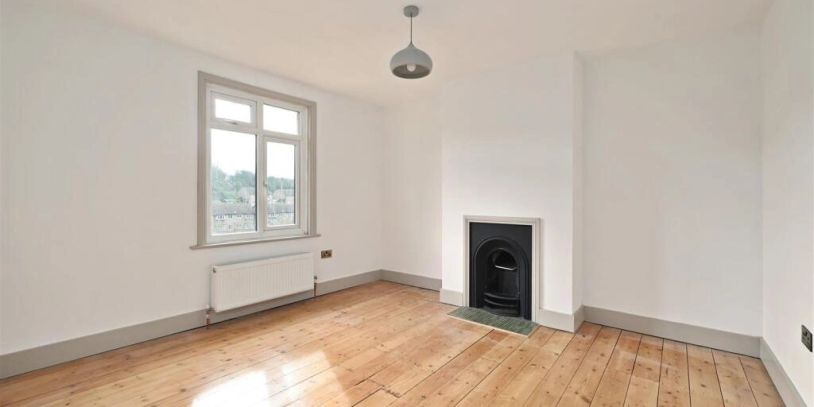 Empty room with wooden floor and fireplace.
