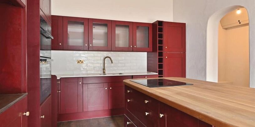 Modern kitchen with red cabinets and wooden island.