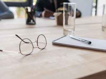 Schreibblock, Stift und Brille auf einem Schreibtisch