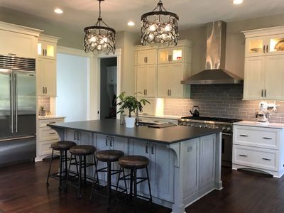 Modern kitchen with island, pendant lights, and stools.