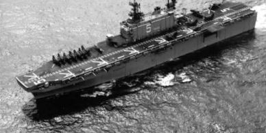 Black and white image of a large naval ship at sea.